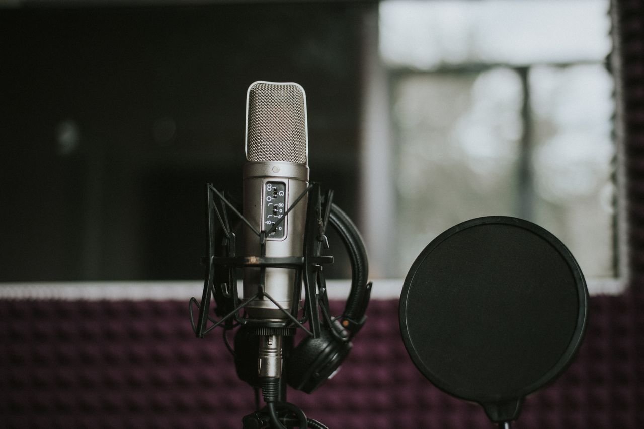 Close-up of a microphone with pop filter in a modern music studio environment.