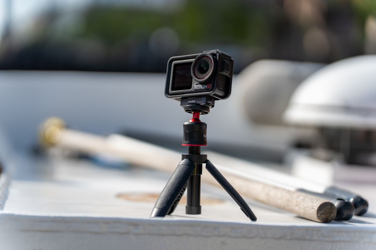 Close-up of a compact action camera mounted on a mini tripod outdoors.